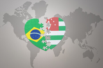 puzzle heart with the national flag of brazil and abkhazia on a world map background.Concept.