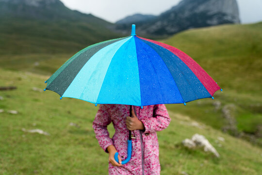 Kid with umbrella under rain. Rainy season and bad weather in mountains. Concept of children protection, safety, security