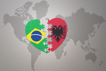 puzzle heart with the national flag of brazil and albania on a world map background.Concept.