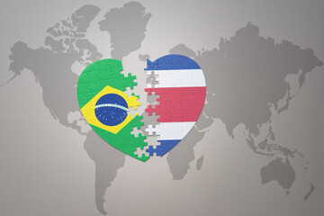 puzzle heart with the national flag of brazil and costa rica on a world map background.Concept.