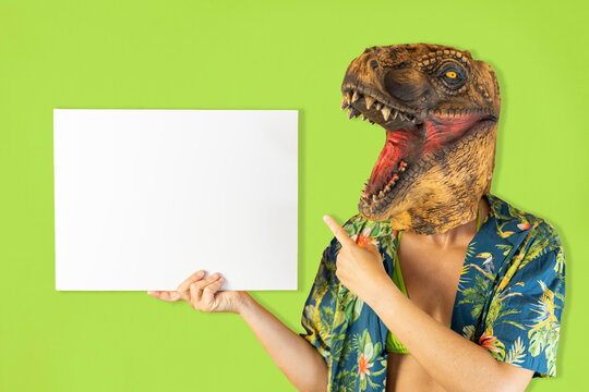 Happy woman wearing tropical shirt and dinosaur animal mask pointing copy space banner holding blank empty white cardboard