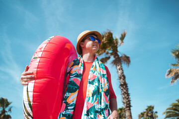 young man with inflatable and towel on his way to the beach. Vacation concept.