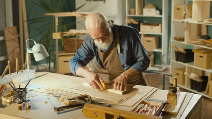 Professional Elderly Man Carpenter Working on Wood Using Carpentry Tools in the Garage. Craft...