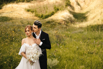 Beautiful newlyweds hugging in nature. Stylish couple together on the background of the hills.