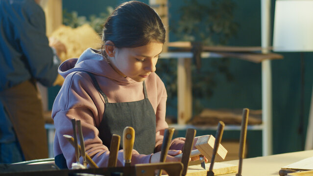 Teen Girl with Carpenter Grandfather Doing Woodcarving with Carpentry Tools in a Cozy Garage. Craft Authentic Workshop. Communication Between Generations, Learning a Craft, Manual Labor, Hobbies.