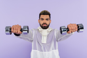 Fototapeta na wymiar bearded african american man exercising with dumbbells isolated on purple.