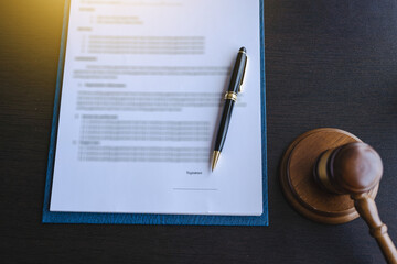 Contract paper on clipboard with lawyer gavel and notebook on black color desk.