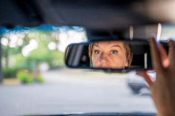 woman's face in the rear view mirror in her car. Woman driving.