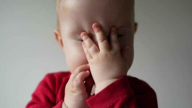 A tired baby of 10 months is tired and rubs his eyes and wants to sleep or cries.