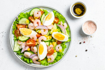 Shrimp egg cucumber tomato salad on plate on light background. Top view, copy space.