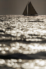 Classic sailing yacht in sea at sunset, the clear sky, sun reflection on water