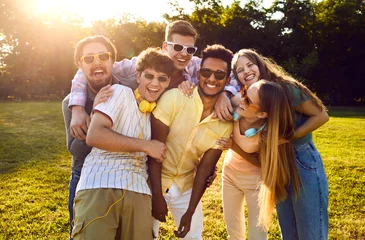 Fotobehang Portrait of happy diverse friends having fun on warm sunny evening in summer park. Bunch of cheerful young people standing on green lawn, smiling and posing for funny group photo together © Studio Romantic