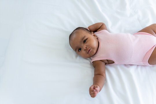 Portrait images of African baby newborn girl is 3 month year old, Lying on white bed in bedroom, to African newborn concept.