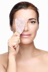 Beautiful naked woman with Gua sha quartz stone for anti-aging massage. Vertical format isolated on...