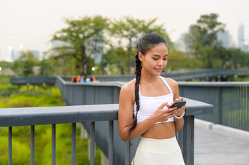 Fototapeta na wymiar Young fitness woman in sportswear using smart phone while exercising in city park, Healthy and Lifestyles.