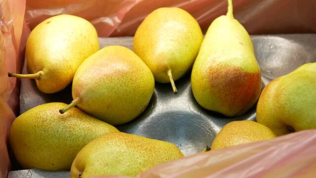Close-up of many beautiful pears in a trading box and a male buyers hand takes one