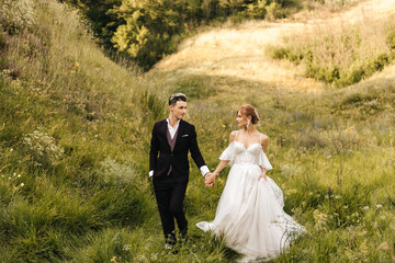 Beautiful couple of newlyweds walking in nature holding hands