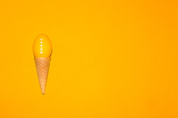 
ice cream cone with ball for american football instead of ice cream ball, creative art design, slow ice cream on yellow background