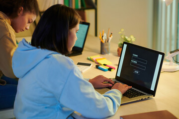 Fototapeta premium Schoolgirl entering e-mail and password to get access to online learning platform