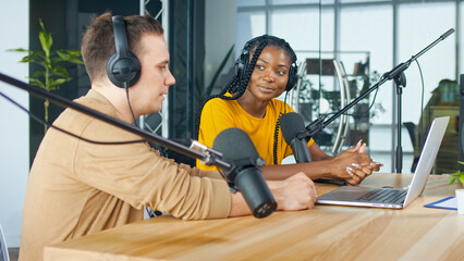 A Male Presenter Communicates with a Guest, an African American, During a Radio Broadcast at a Table in a Recording Studio, Broadcasts a Live Radio Interview With Spbd. - obrazy, fototapety, plakaty
