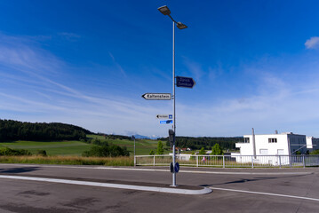 Direction signs with street lights and scenic rural landscape at village Forch, Canton Zürich, on a sunny summer day. Photo taken June 8th, 2022, Forch, Switzerland.