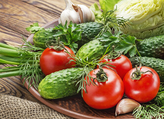 Fresh organic vegetables tomatoes, onions, cucumbers in a plate.