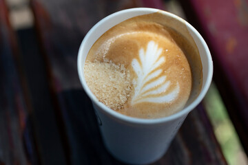 Cappuccino in a paper cup with brown sugar