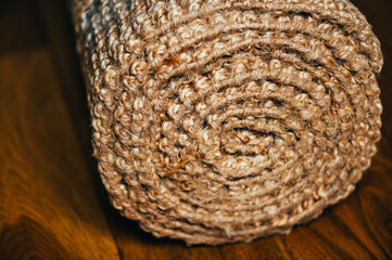 Obraz premium New rolled jute rug with chunky texture on oak flooring, natural fiber carpet, eco friendly home interior concept, shallow DoF