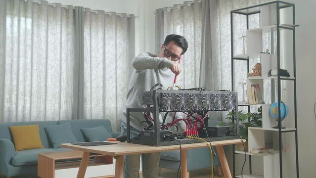 Asian Man Wearing Glasses Cleans The Mining Rig For Mining Cryptocurrency 
