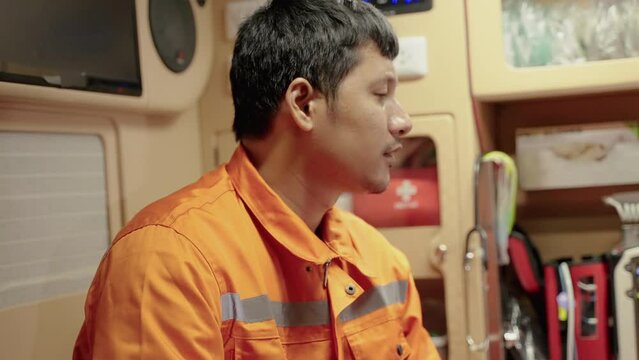 Asian paramedic worker is sitting in a car to pick up a patient with a tense expression on his face and anxious
