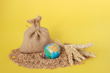 Wheat, grain in a bag, mini globe on a yellow background. Harvest concept. Export Import. Food...