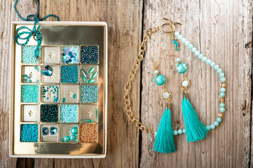 different azure beads and chrystals in box handmade jewelry  around old style wooden background. close up