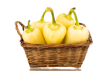 Several bright yellow sweet peppers in a basket, close-up, isolated on a white background.