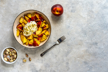Healthy fruit salad with nectarine, ricotta cream with pistachios and honey, Top view. Copy space