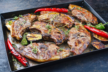 Gegrillte Lammrückensteaks mit Chili und Kräuter serviert als close-up auf einem rustikalen Metall Tablett