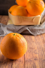 in the foreground an orange and behind, in the background, more oranges in a wooden box