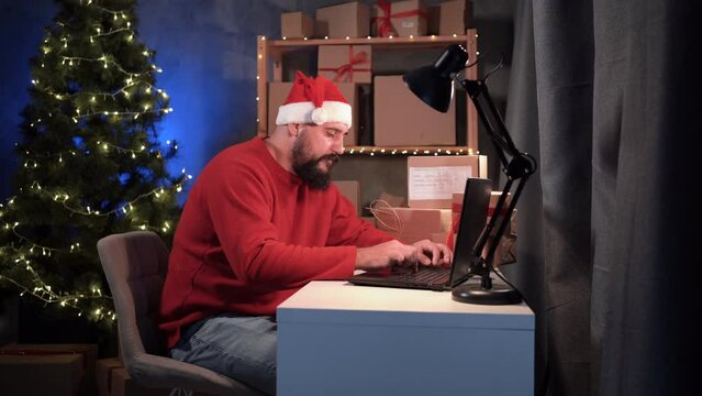 Indian male dropshipper owner working at home office at night on laptop, checking order for confirmation before shipping to customer during Christmas sale. Online store and small business.