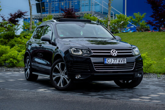 Cluj-Napoca, Cluj-Romania-06.13.2022-Beautiful Exclusive VW Touareg black metallic paint with 20-inch rims, panoramic sunroof, and daylight headlights isolated in an empty parking lot