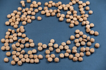 Close-up of dry pet food pellets against a gray background. Brown round pellets. Healthy food for...