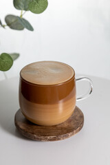 Cafe latte macchiato layered coffee in a see through glass coffee cup. The cup is on a white background .