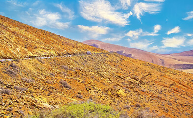 Beautiful wild arid valley landscape, serpentine road, blue sky fluffy clouds - Betancuria (montana atalaya), Lanzarote