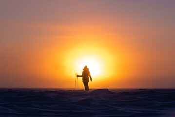 Beautiful arctic sunrise in northern Canada during peak wintertime. Woman silhouette standing in front of bright, blazing sun.	