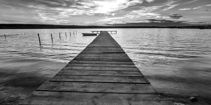 black and white at the shore with wooden pier and moored boat