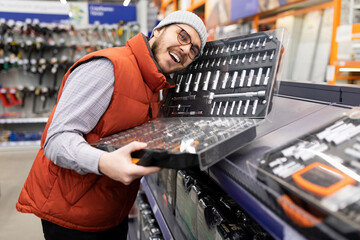 satisfied man holding set of socket and wrench heads in hardware store - obrazy, fototapety, plakaty