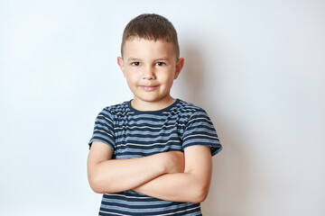 Little smiling boy posing with folded arms.