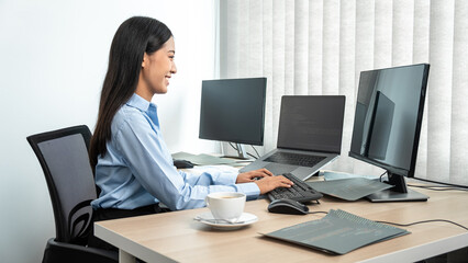 Female programmer using multiple monitor screen to development business website while working to...