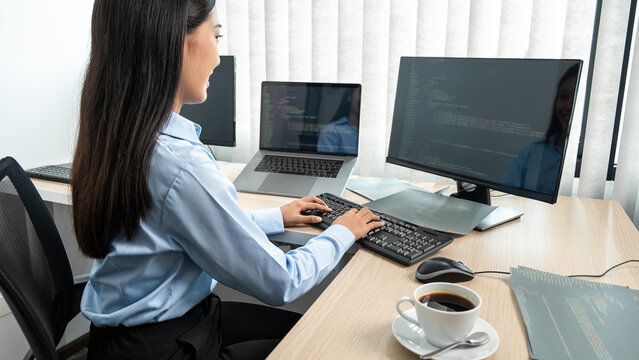 Female programmer using multiple monitor screen to development business website while working to typing HTML data code