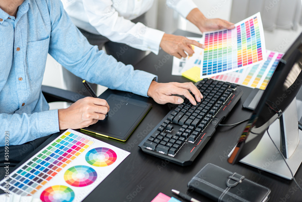 Poster Team graphic designer working on document of color chart to brainstorming about new project and using laptop