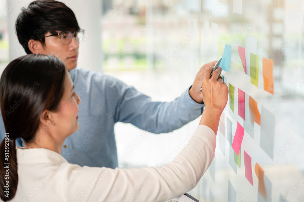 Poster two business executive team holding and taking notes keyword on board wall to brainstorm about a new