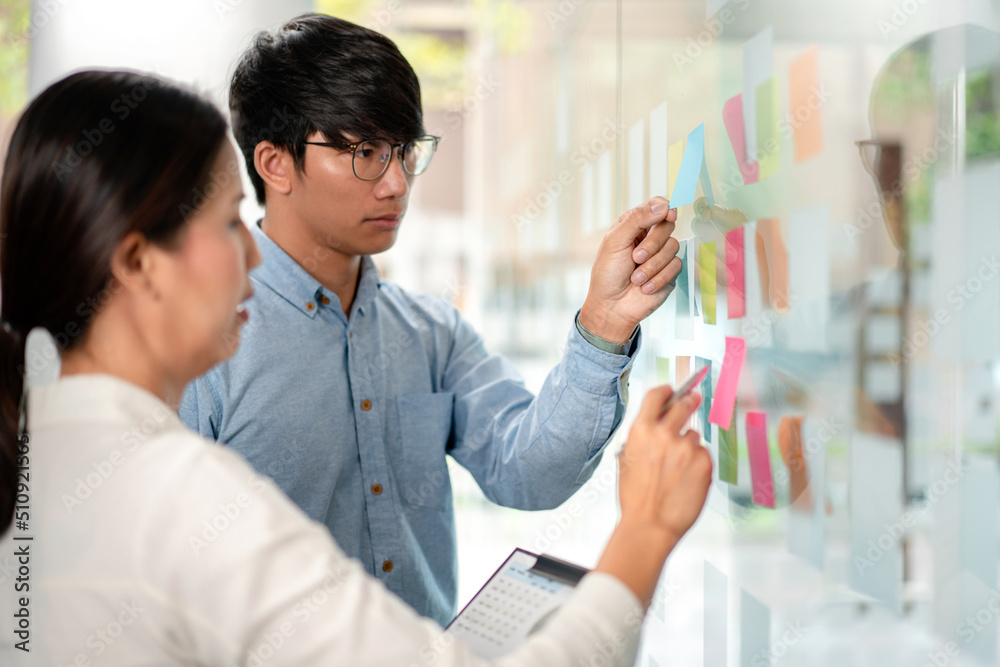 Poster two business executive team holding and taking notes keyword on board wall to brainstorm about a new